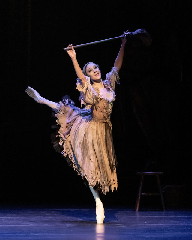 Ballerina på tåspiss som løfter en kost