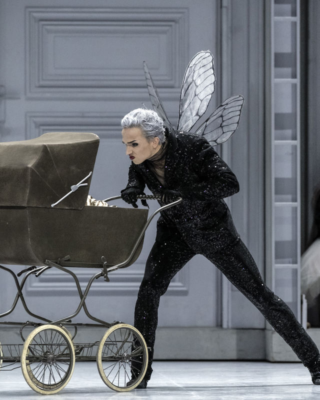 en sint mann med fe-vinger triller en barnevogn