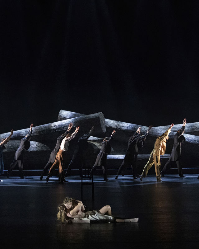 en stor gruppe dansere foran store trestokker