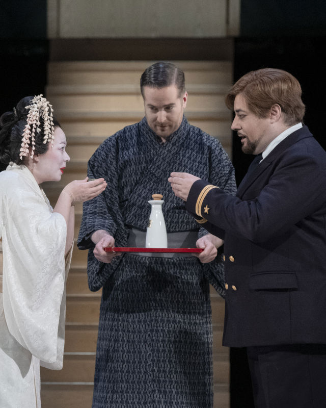 Kvinne i japansk brudedrakt skåler med mann i uniform, mann i kimono med flaske på serveringsbrett