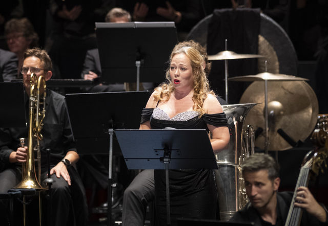 Kvinne i konsertkjole blant orkestermusikere