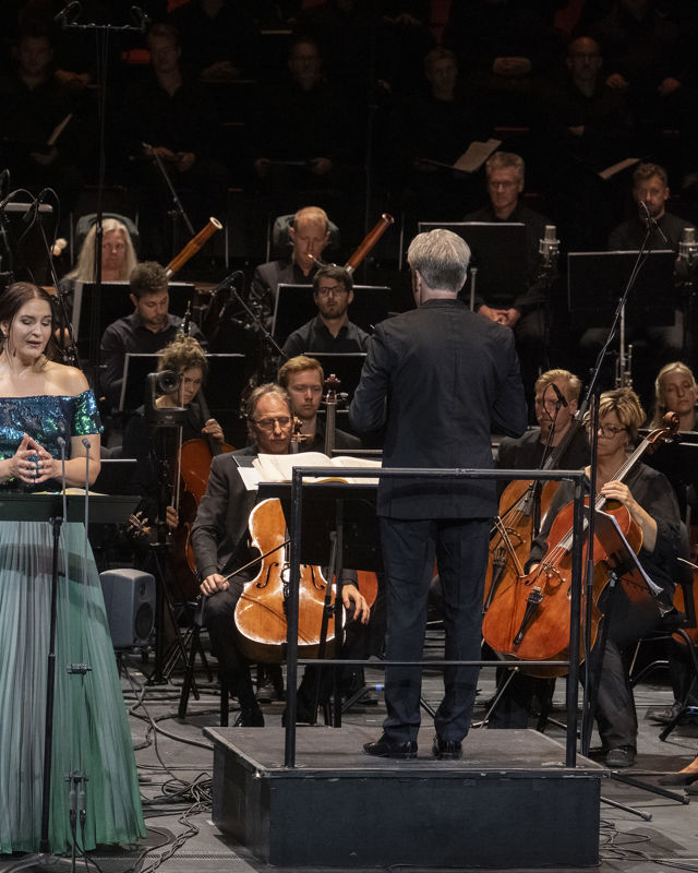 Kvinne i grønn kjole foran orkester
