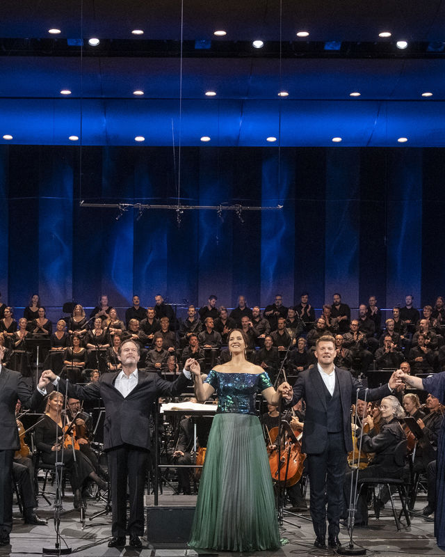 Flere sangere foran stort orkester og kor
