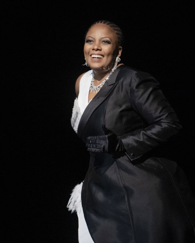 kvinne i svart og hvit kjole mot mørk bakgrunn