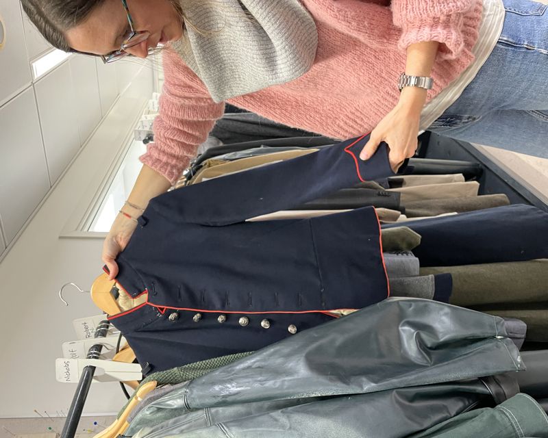 Kvinne holder frem uniformsjakke fra klesstativ