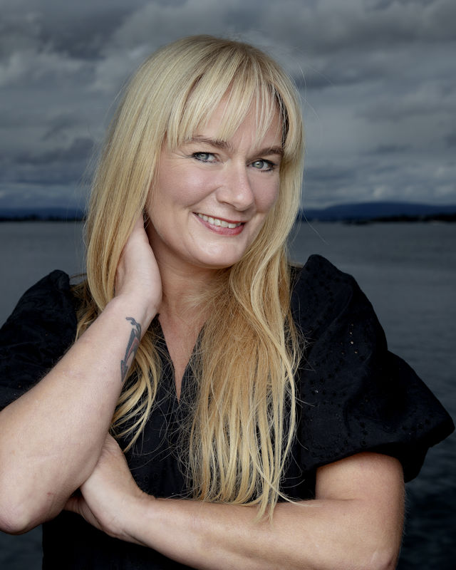 Portrett av kvinne foran sjø og dramatisk himmel