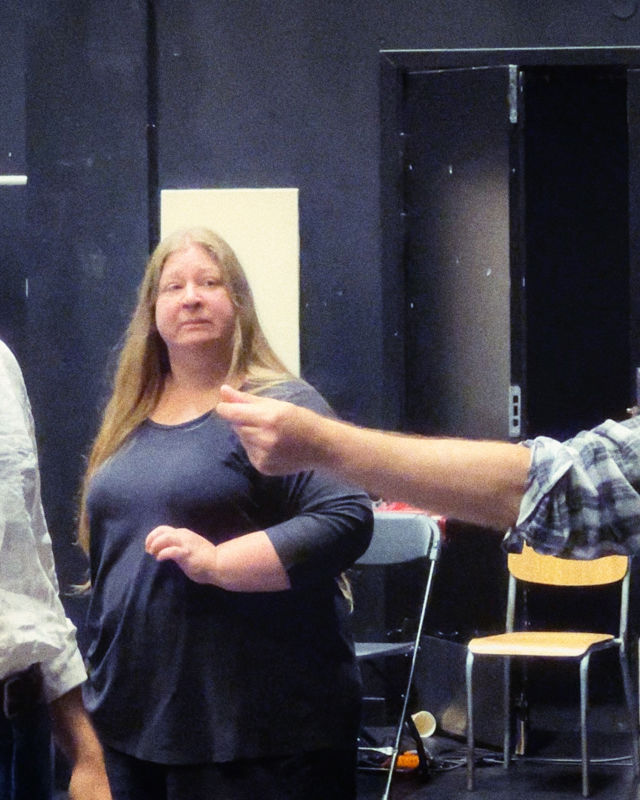 Mann med rutete skjorte instruerer en gruppe mennesker