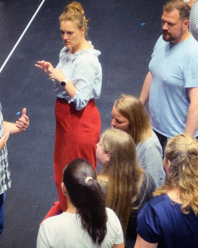 Mann med rutete skjorte instruerer en gruppe mennesker