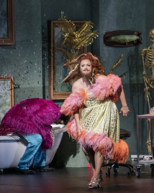 Kvinne med skjegg og kjole med pelskanter kommer løpende